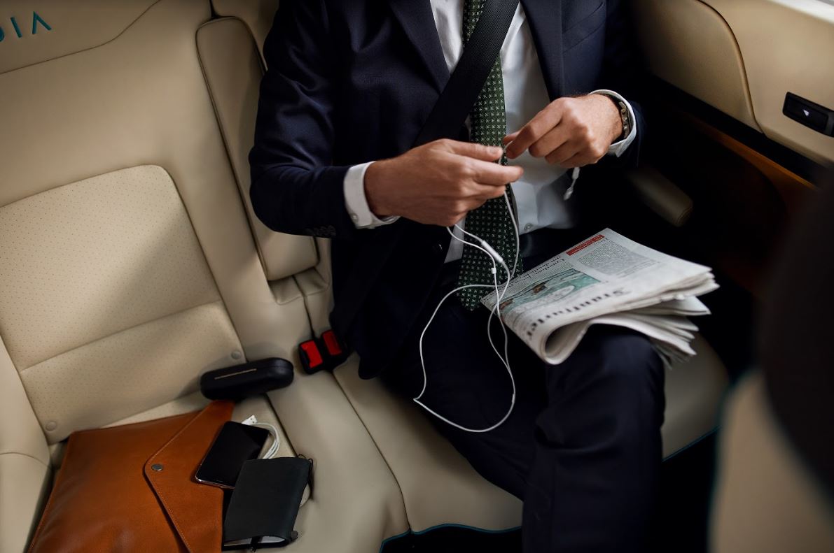 A man in a suit sitting in a MOIA. Several valuables are lying on the seat next to him.